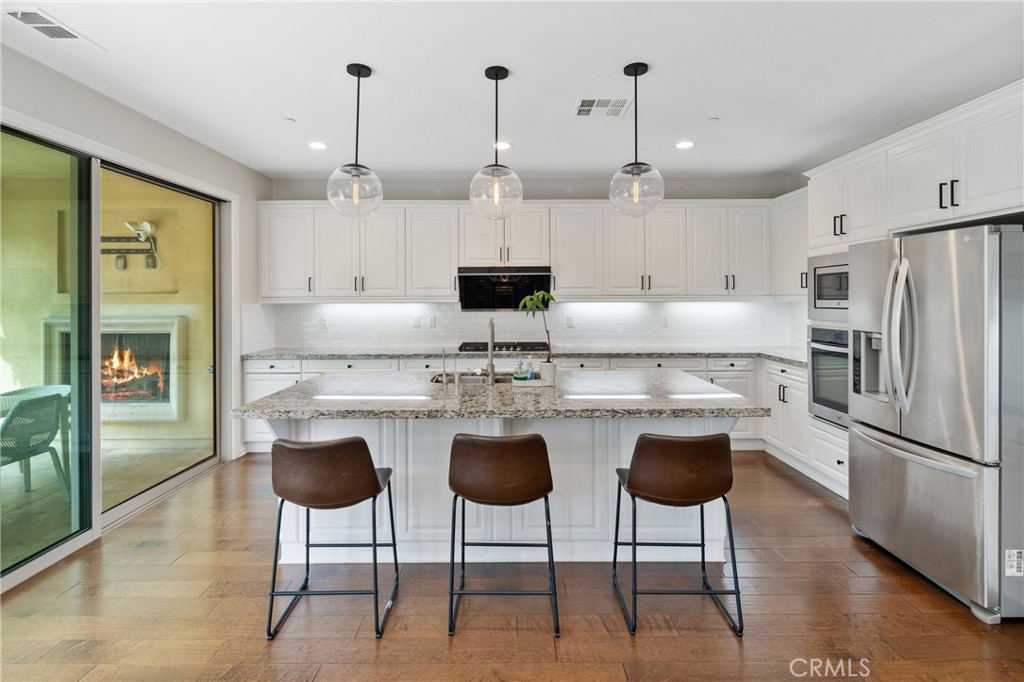323 La Ventana Drive Brea, CA 92823 - Photo 2 of 47 a kitchen with stainless steel appliances granite countertop a sink a stove a refrigerator and a dining table with wooden floor