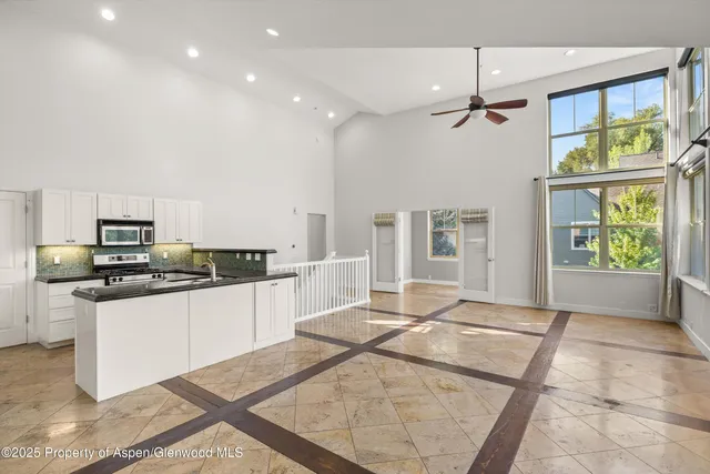 a large kitchen with stainless steel appliances kitchen island granite countertop a refrigerator and a stove top oven