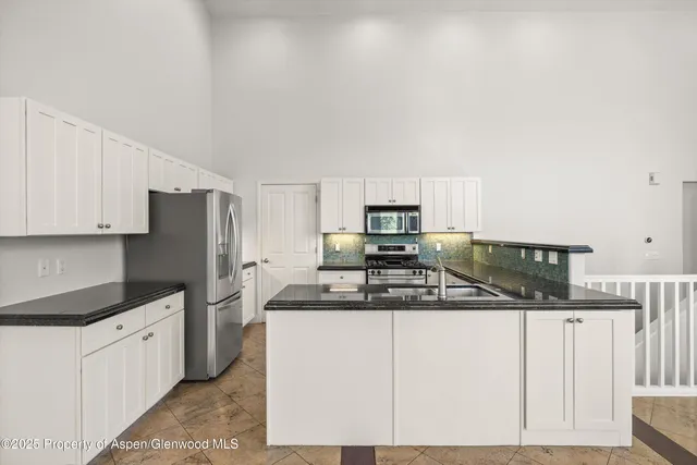 a kitchen with stainless steel appliances granite countertop a sink a stove a refrigerator a microwave and cabinets