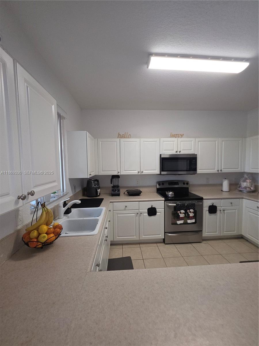 13236 Southwest 128th Street Miami, FL 33186 - Photo 13 of 41 a kitchen with stainless steel appliances a stove a sink and white cabinets