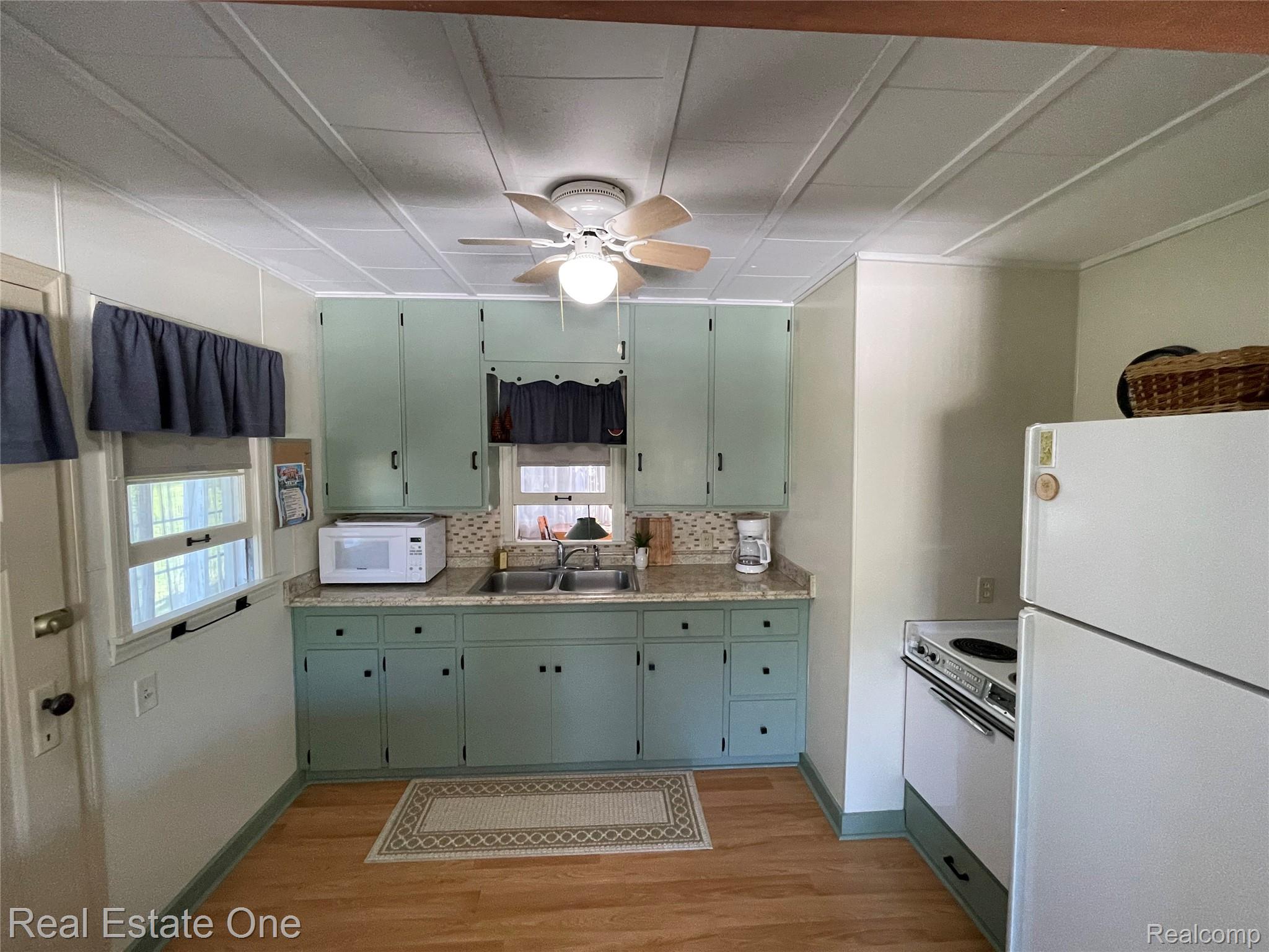 4160 Hawk Road Lincoln, MI 48742 - Photo 12 of 48 Kitchen featuring light green cabinetry, light wood-finish flooring, and a patterned backsplash