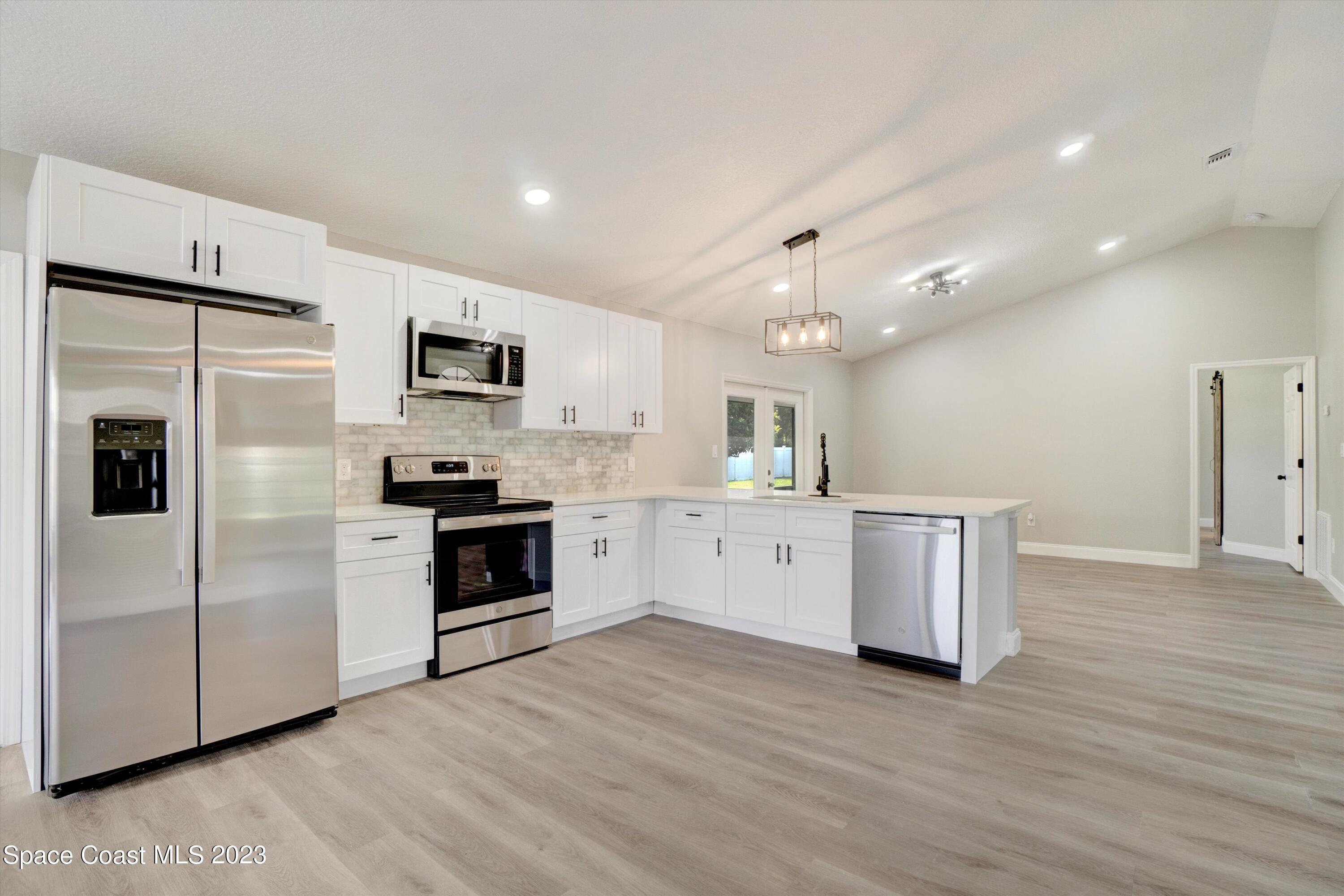207 Eldron Boulevard Southeast Palm Bay, FL 32909 - Photo 14 of 60 a kitchen with a refrigerator and a stove top oven