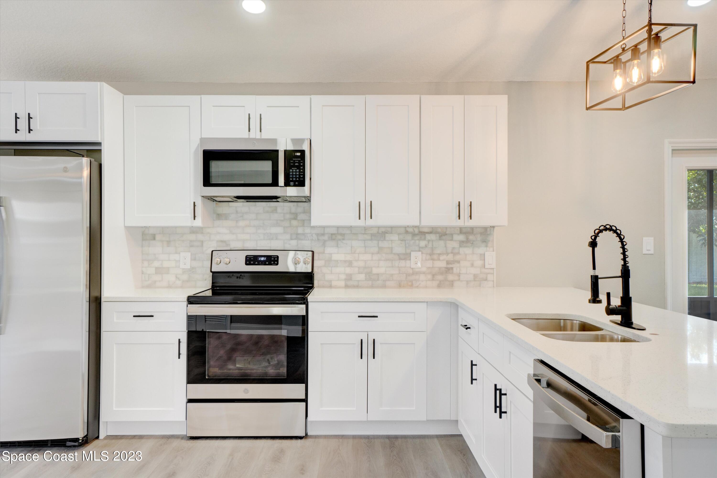 207 Eldron Boulevard Southeast Palm Bay, FL 32909 - Photo 15 of 60 a kitchen with white cabinets and stainless steel appliances