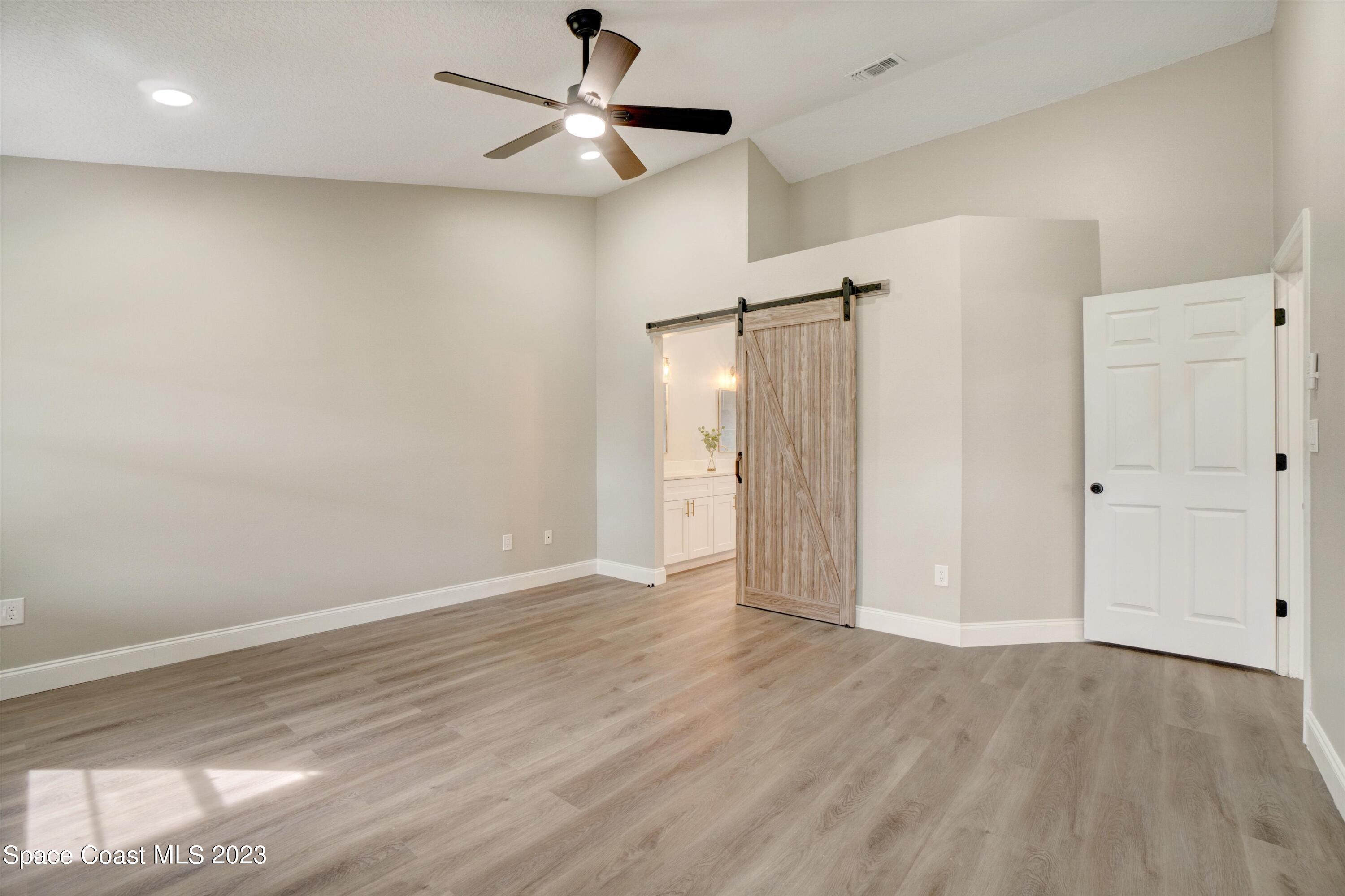 207 Eldron Boulevard Southeast Palm Bay, FL 32909 - Photo 24 of 60 an empty room with wooden floor fan and windows