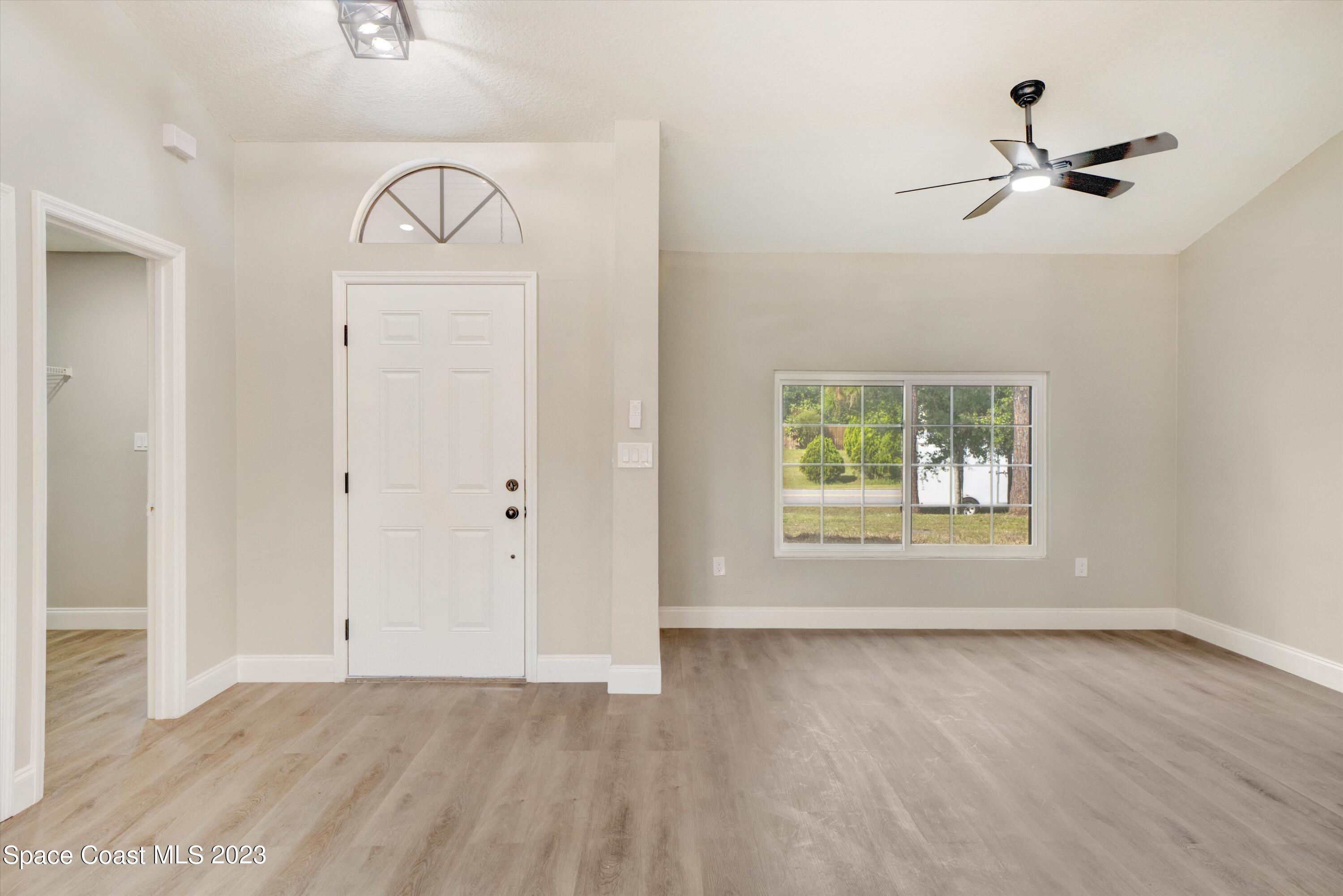207 Eldron Boulevard Southeast Palm Bay, FL 32909 - Photo 7 of 60 an empty room with wooden floor closet and windows