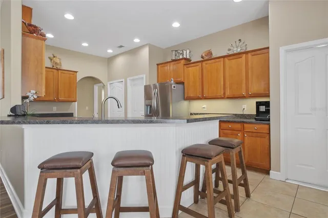 a kitchen with stainless steel appliances granite countertop a table chairs sink and cabinets