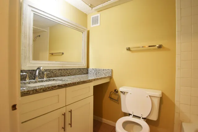 a bathroom with a granite countertop toilet sink and mirror