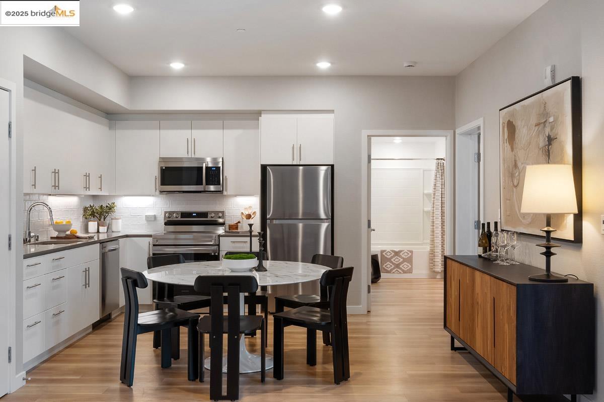 260 Brooklyn Basin Way, Unit 417 Oakland, CA 94606 - Photo 6 of 48 Kitchen featuring backsplash, appliances with stainless steel finishes, light wood-type flooring, white cabinetry, and recessed lighting