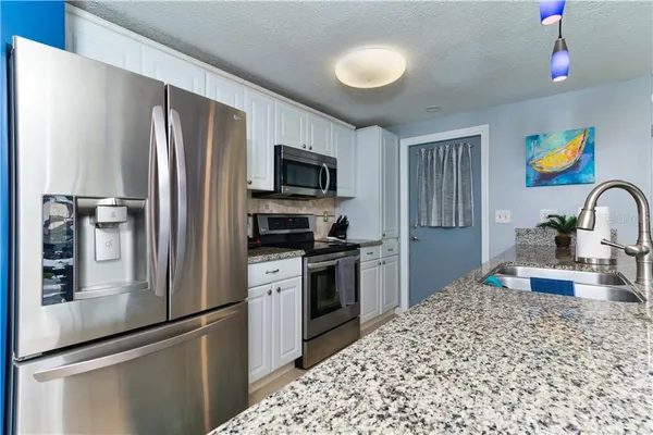 a kitchen with stainless steel appliances granite countertop a sink and a refrigerator