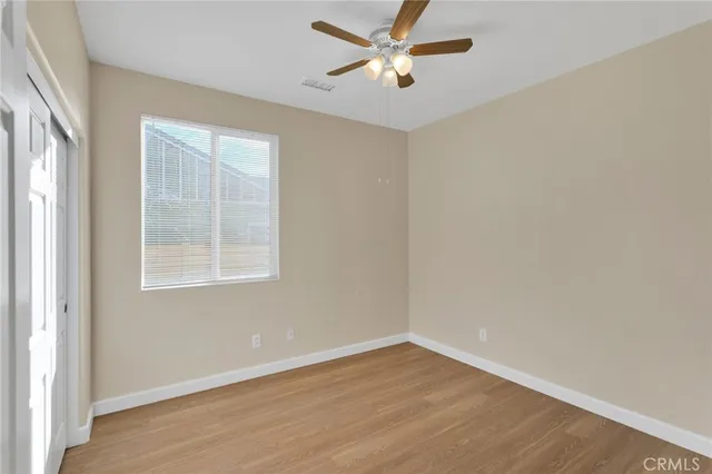 a view of empty room with wooden floor and fan