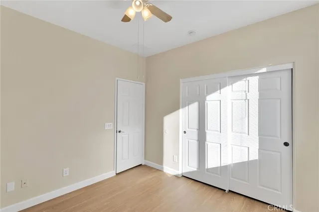 an empty room with chandelier fan and windows