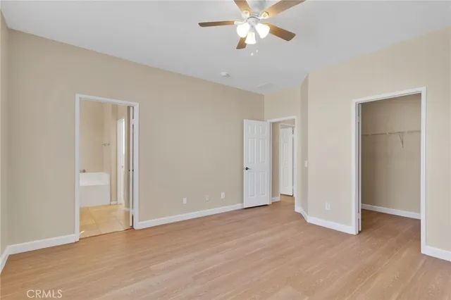 an empty room with wooden floor and ceiling fan