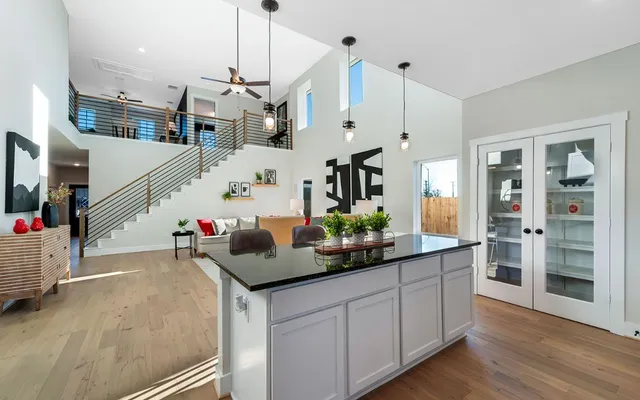 a kitchen with stainless steel appliances kitchen island granite countertop a dining table chairs and white cabinets