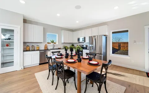 a living room with furniture and a dining table with wooden floor