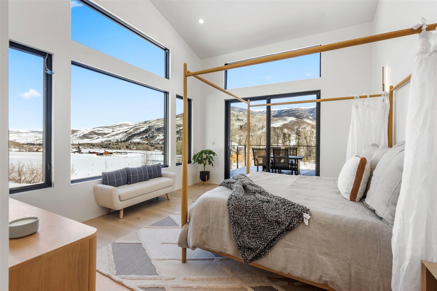 Bedroom with a mountain view, vaulted ceiling, multiple windows, and light hardwood / wood-style flooring