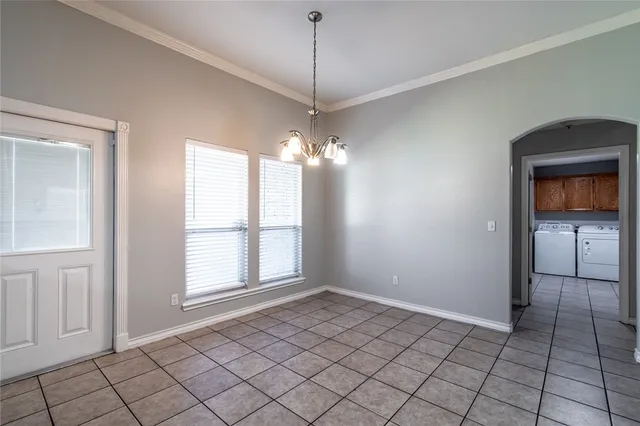 a view of an empty room with window and chandelier fan