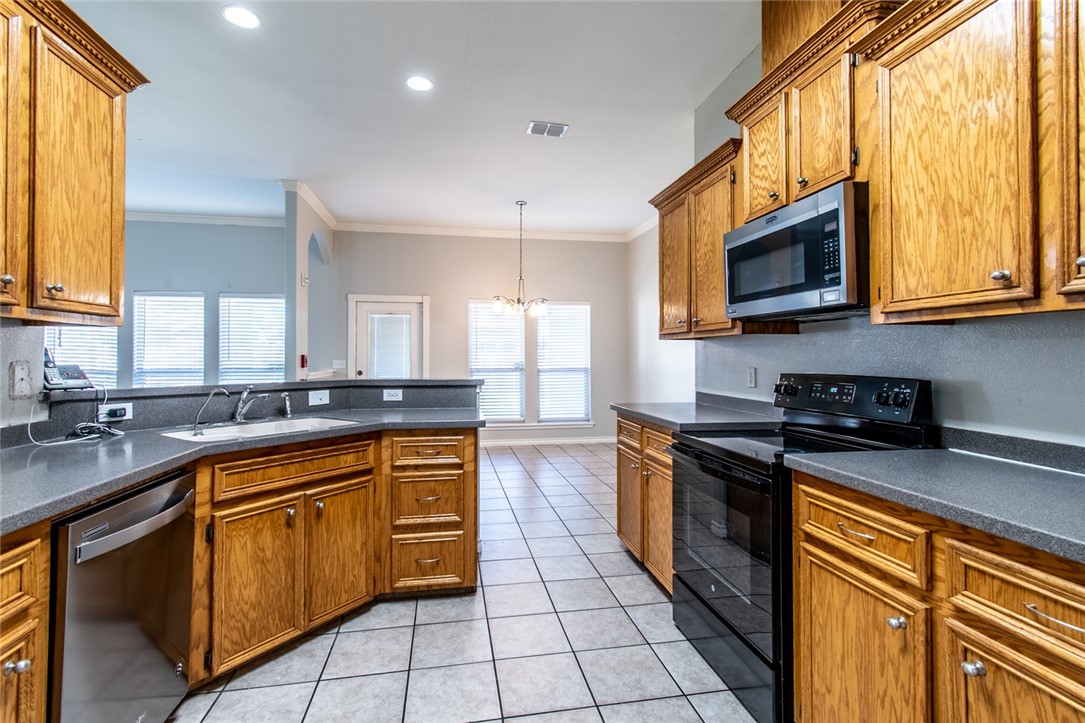103 Collins Street Odem, TX 78370 - Photo 10 of 32 a kitchen with stainless steel appliances granite countertop wooden cabinets a stove a sink and a microwave