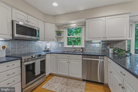 a kitchen with granite countertop wooden floor dining table and stainless steel appliances