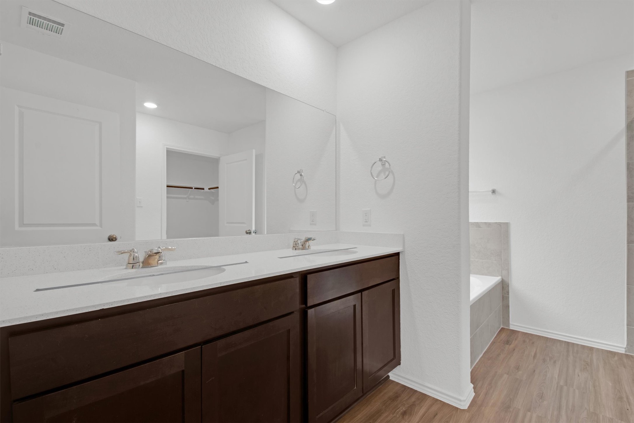 703 Bluejack Way Hutto, TX 78634 - Photo 12 of 19 Bathroom with double vanity, light wood-style floors, tiled tub, a walk in closet, and recessed lighting