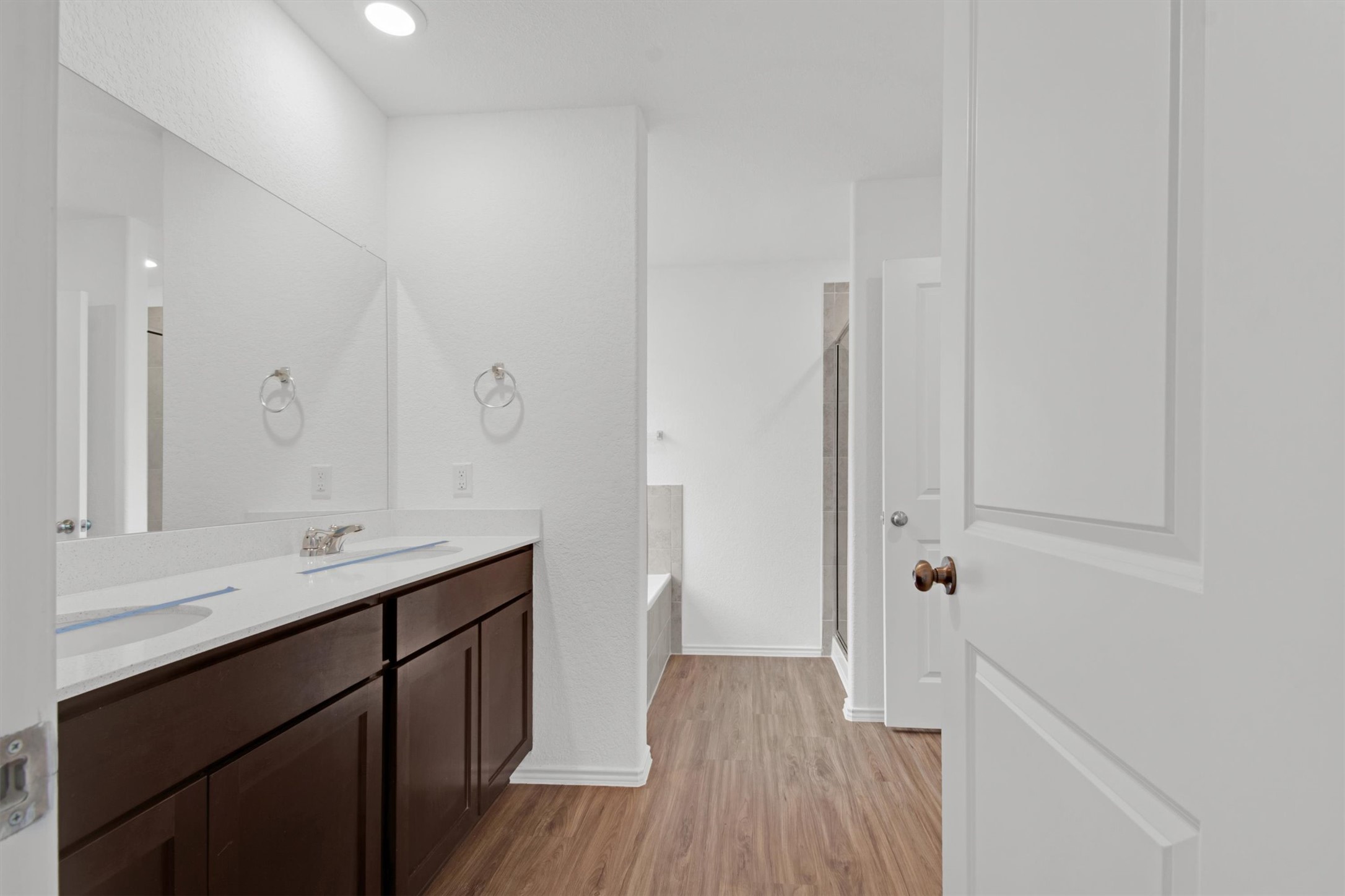 703 Bluejack Way Hutto, TX 78634 - Photo 7 of 19 Bathroom featuring a bath, double vanity, a stall shower, and light wood-style floors