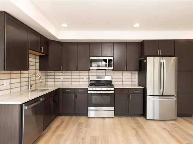 a kitchen with stainless steel appliances granite countertop a refrigerator a sink dishwasher a stove and a refrigerator