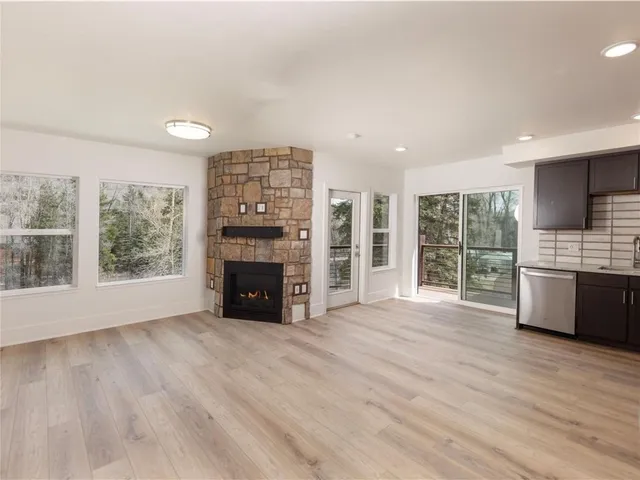 a view of an empty room with a window and kitchen view