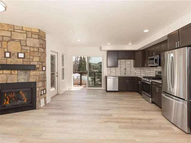 a large kitchen with stainless steel appliances granite countertop a refrigerator a stove oven a sink and dishwasher with wooden floor