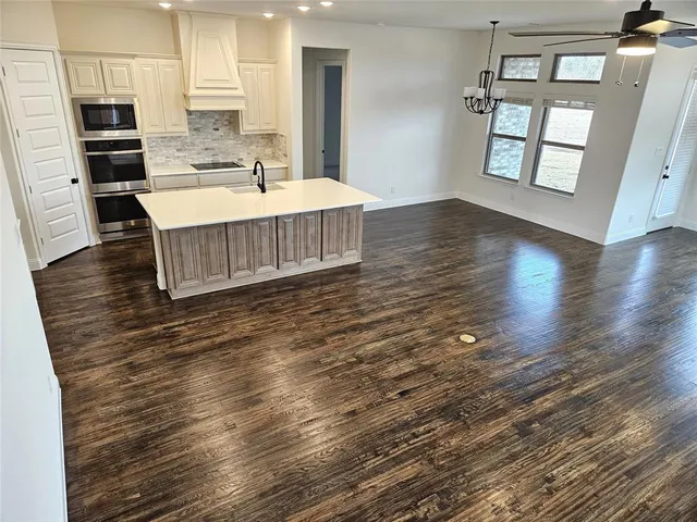 a large white kitchen with wooden floor and a refrigerator