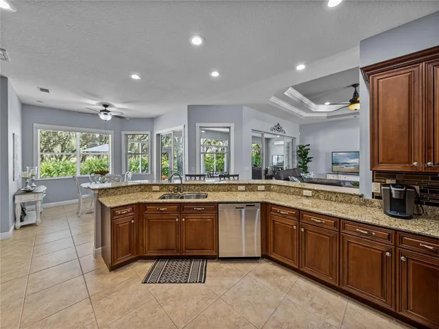 a large kitchen with kitchen island granite countertop a sink and dishwasher wooden cabinets with granite countertops
