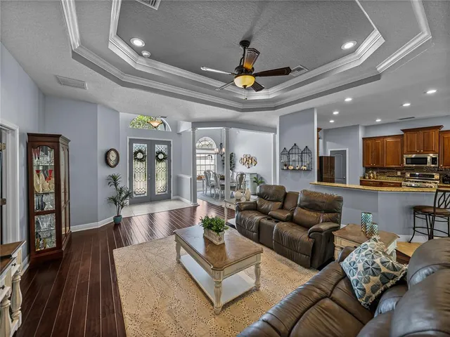 a living room with furniture kitchen view and a wooden floor