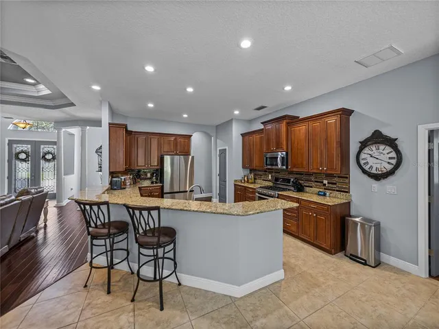 a kitchen with stainless steel appliances granite countertop a table chairs and a refrigerator