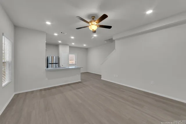 an empty room with wooden floor and windows