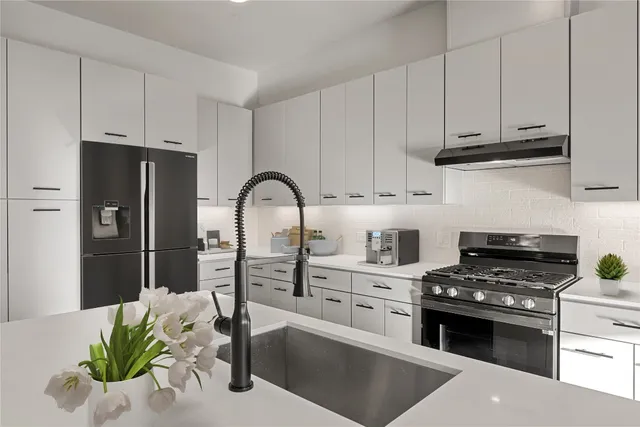 a kitchen with stainless steel appliances kitchen island granite countertop a refrigerator a stove a sink and white cabinets