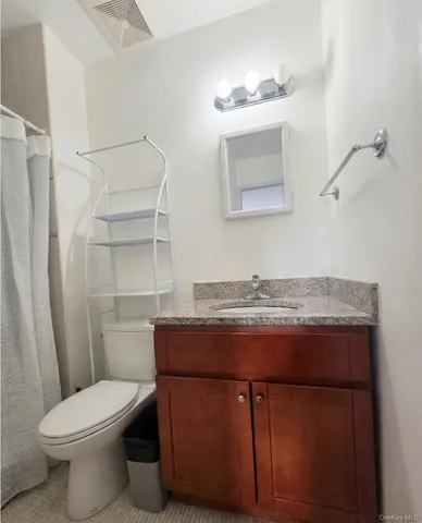 a bathroom with a granite countertop toilet sink and mirror