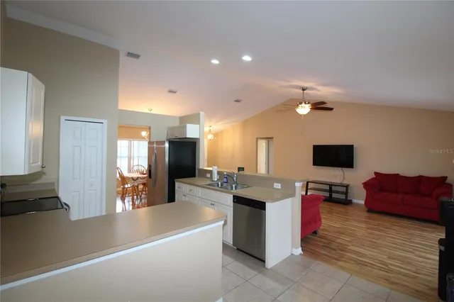 a large living room with stainless steel appliances kitchen island a table chairs in it and a flat screen tv