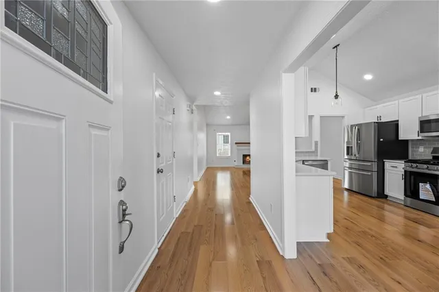 a kitchen with stainless steel appliances granite countertop a stove top oven a refrigerator a sink and dishwasher with wooden floor