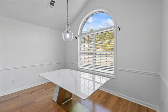 a view of an empty room with wooden floor fireplace and a window