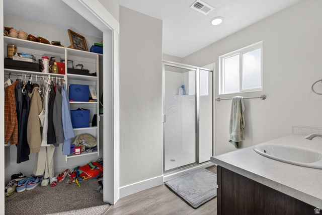 412 McClellan Court Provo, UT 84601 - Photo 15 of 20 Bathroom featuring a stall shower, vanity, light wood-style flooring, and a walk in closet