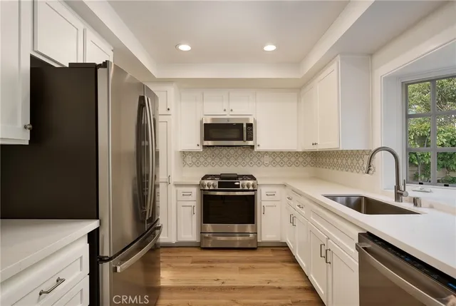 a kitchen with white cabinets and appliances