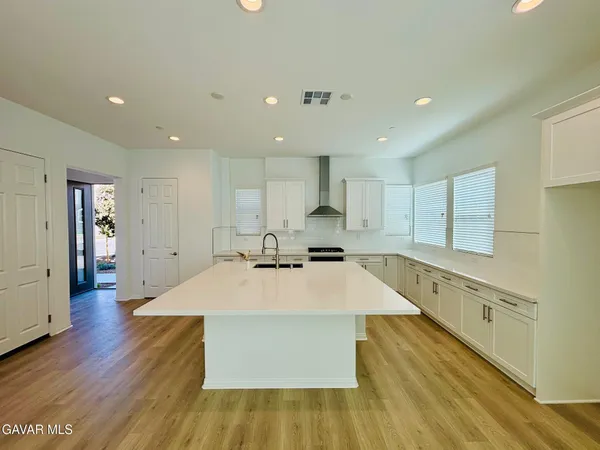 a large kitchen with stainless steel appliances lots of counter space and wooden floors