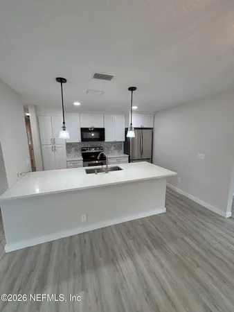 a view of a kitchen counter space a sink and wooden floor