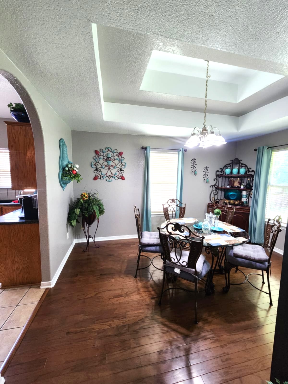 Elegant tray ceilings crown a formal dining area boasting rich hardwood floors.