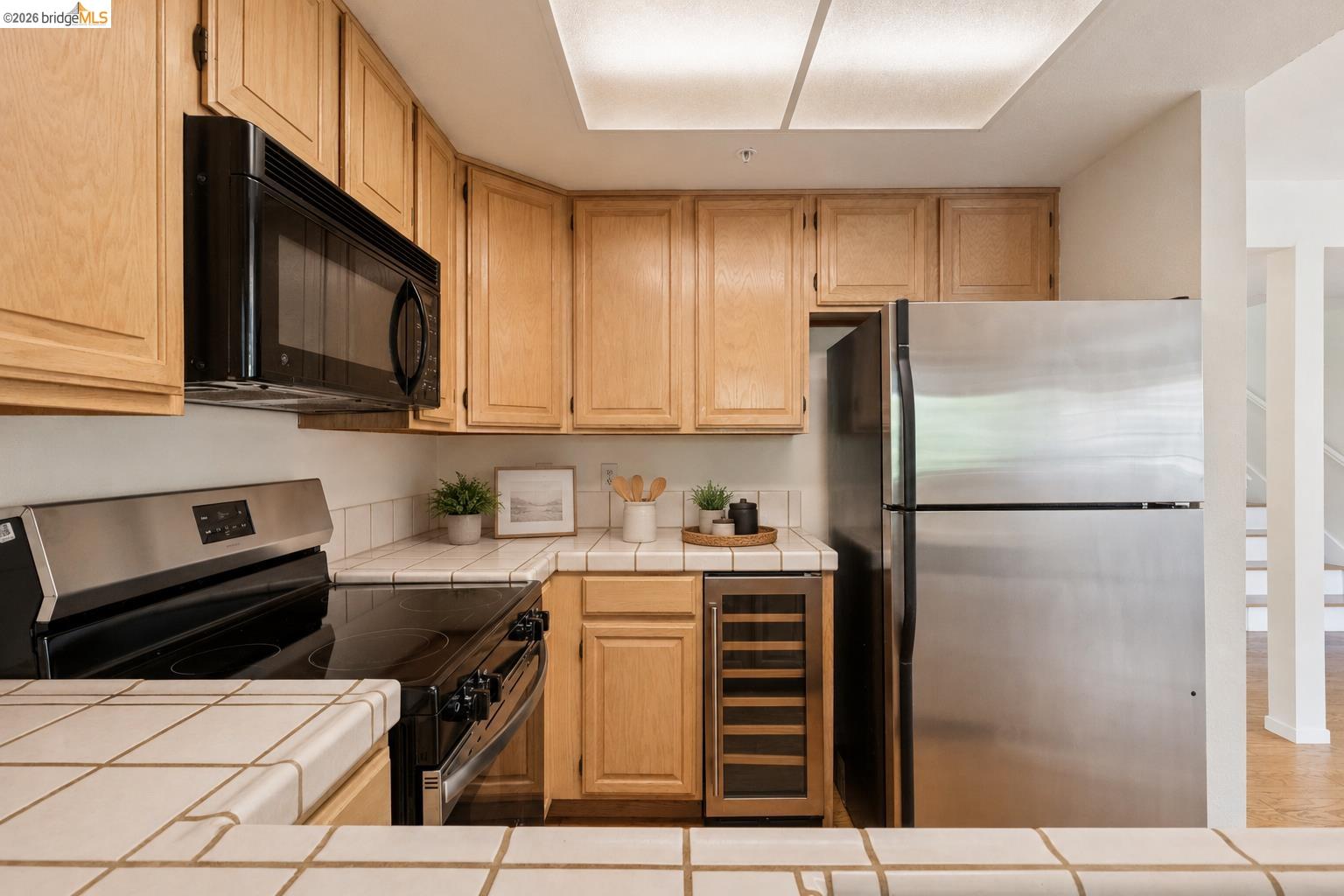 261 Redhawk Road Novato, CA 94949 - Photo 20 of 44 Kitchen featuring light wood cabinetry, white tile countertops, stainless steel refrigerator, black range, and built-in microwave