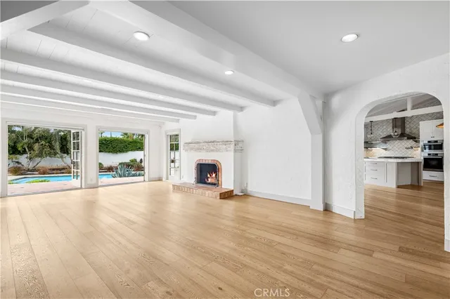 an empty room with wooden floor a fireplace and windows