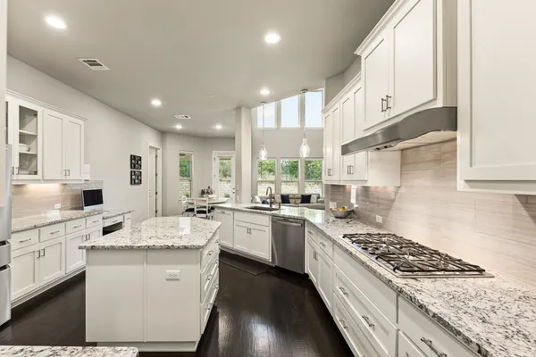 a large kitchen with stainless steel appliances granite countertop a stove a sink dishwasher and a refrigerator