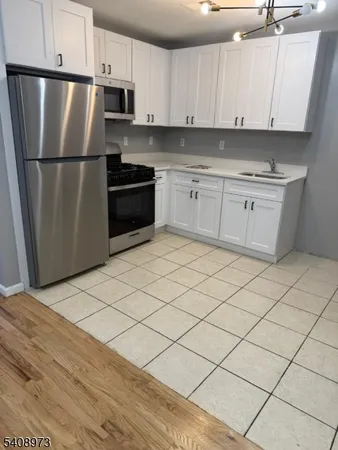 a kitchen with a sink a refrigerator and white cabinets