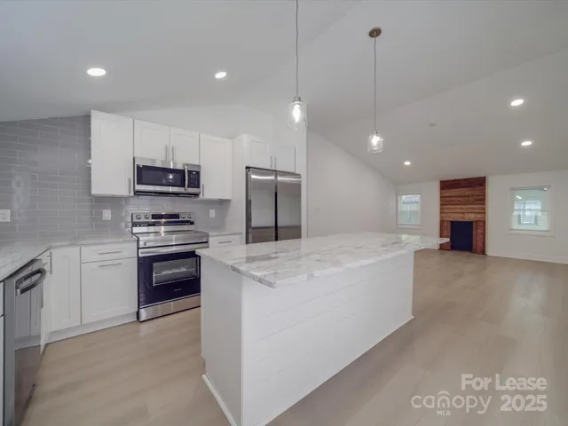 a kitchen with stainless steel appliances kitchen island granite countertop a stove a refrigerator and a sink