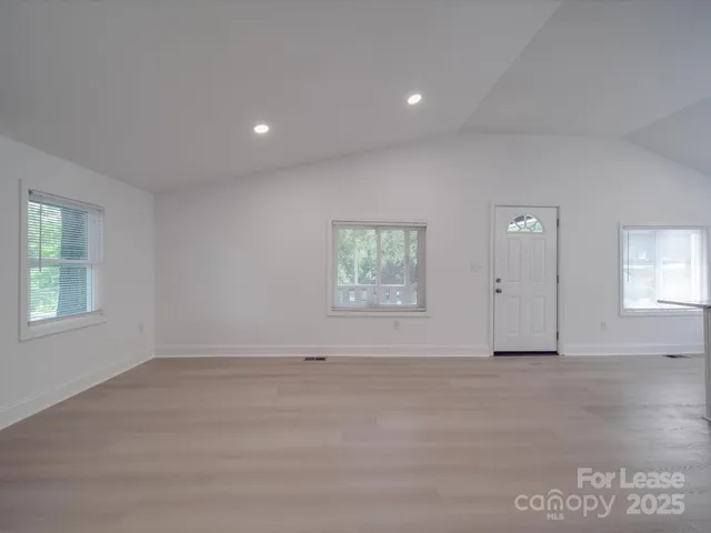 an empty room with windows and fireplace
