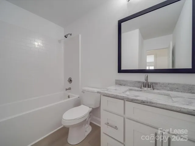 a bathroom with a granite countertop toilet sink and mirror