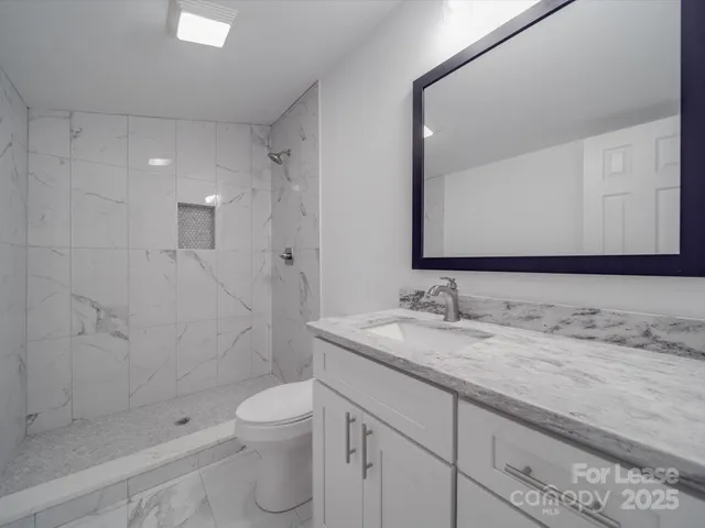 a bathroom with a granite countertop sink a toilet and shower